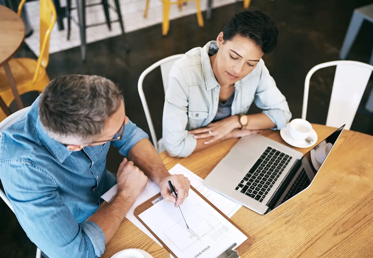 a group of people sitting at a table using a laptop computer