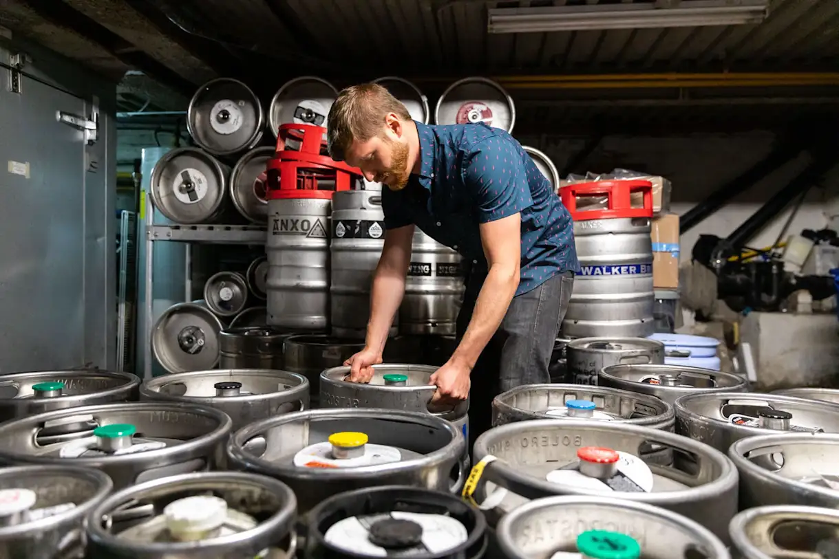 Zach Mack organizing kegs of beer in a basement.