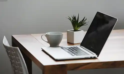 a desk with a laptop computer sitting on top of a wooden table
