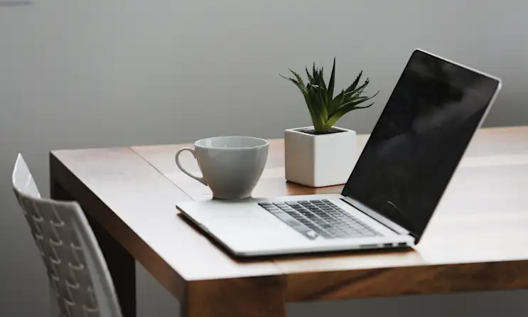 a desk with a laptop computer sitting on top of a wooden table