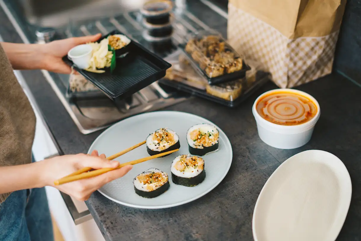 a woman plating sushi from a to-go box