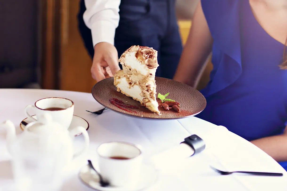 a woman sitting at a table with a cake on a plate