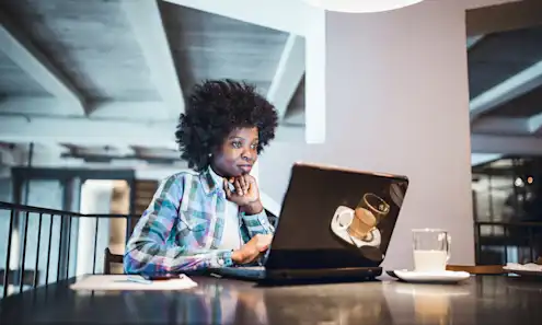 a woman sitting at a table using a laptop computer