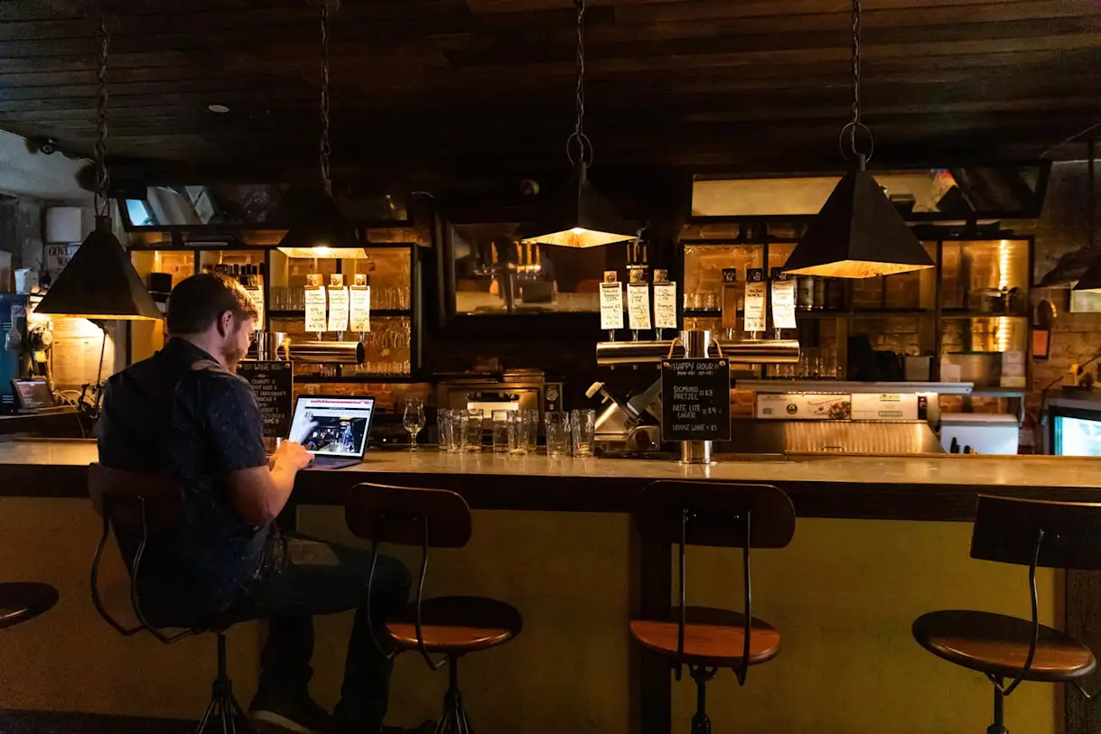 Zach Mack working on his laptop sitting at a wooden bar.