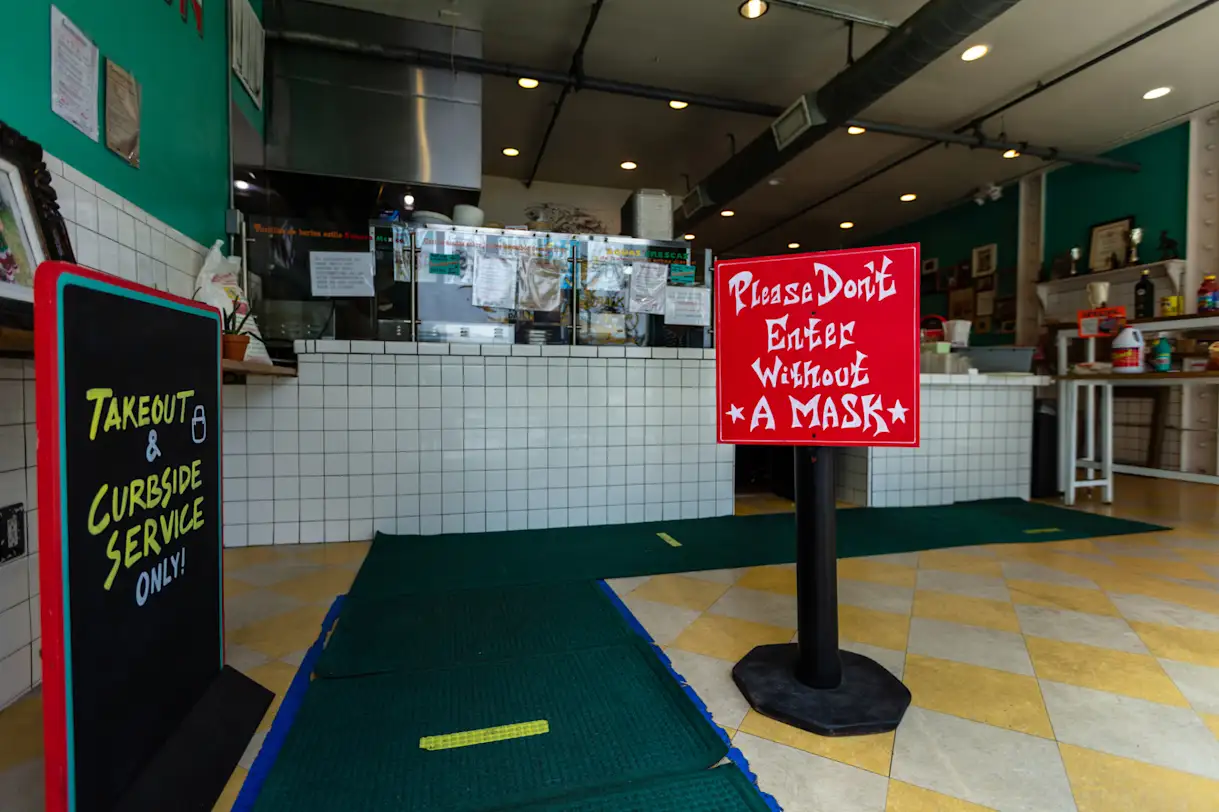 the entrance to a restaurant during COVID-19 with a sign that reads to-go and curbside service only