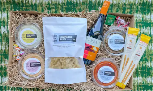 Gift box filled with dips, pasta, wine, and breadsticks