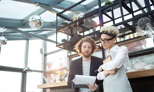 Man and woman review restaurant licensing paperwork while standing side by side