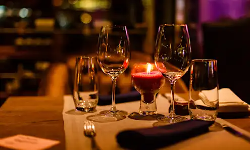 Two water glasses, two wine glasses, and a pink candle in the middle of a restaurant table