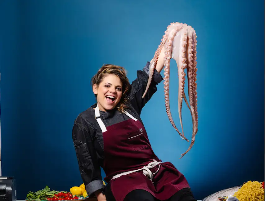 a person posing for the camera with an octopus in hand.